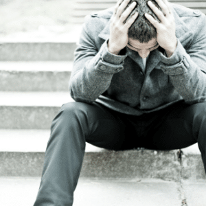 Photo of man sitting on step, upset with head in hands for Suicide Intervention Workshop