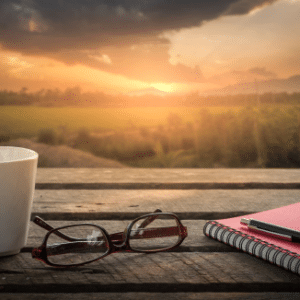 Photo of a table with a journal and coffee mug with a sunset or sunrise in the background for Wellness Strategies - Stress, Compassion Fatigue, and Resilience workshop